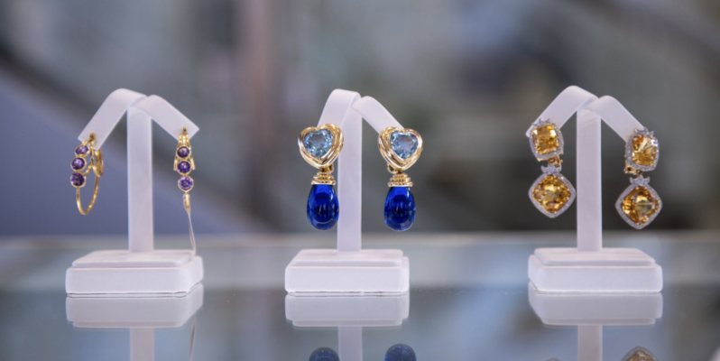 Three pairs of gemstone jewelry on displays.